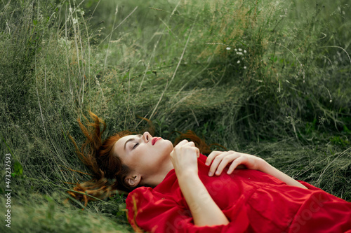 pretty woman in red dress lies on the grass in the field nature fresh air © VICHIZH