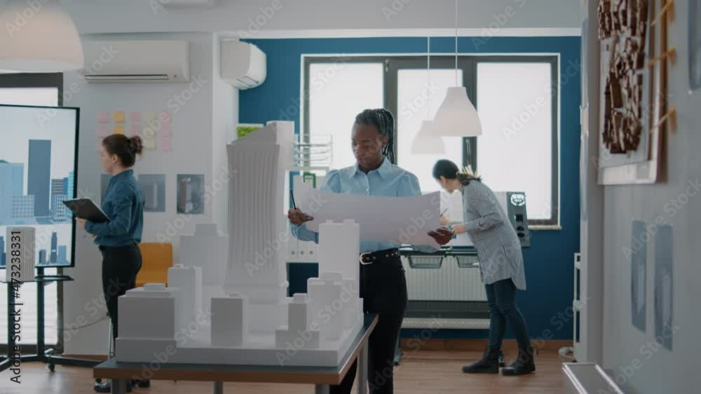 Portrait of woman architect analyzing blueprints plans on paper to design building model and maquette. Employee looking at construction sketch to plan architectural layout structure. Portrait of woman architect analyzing blueprints plans on paper to design building model and maquette. Employee looking at construction sketch to plan architectural layout structure.