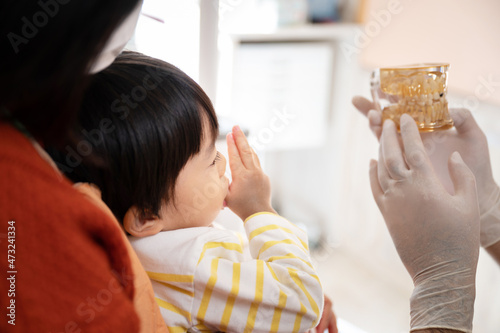 Fotografie 模型を使って子供の患者の指しゃぶりの説明する小児歯科医