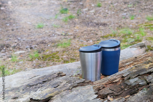 Tourist food for outdoor activities. Thermo cups on a in the wild forest for trevelers. Enjoy a tasty coffee during trips. © Ga_Na