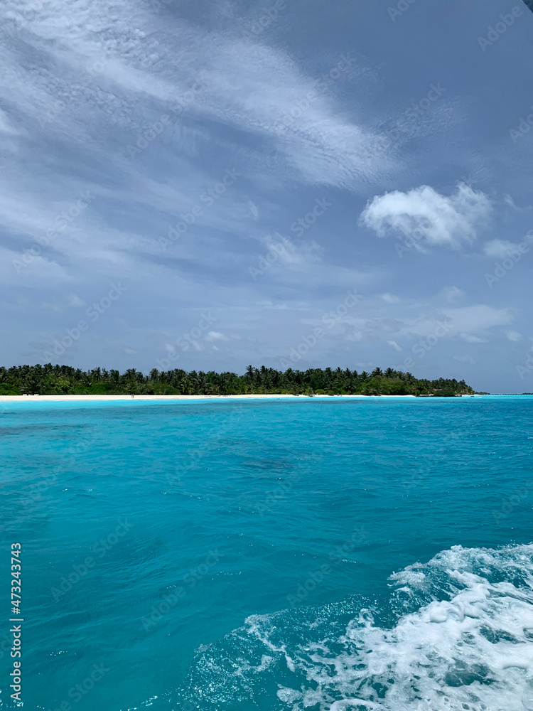 View of a white sand beach on the Maldives island from a boat in the turquoise water of the Indian Ocean View of a white sand beach on the Maldives island from a boat in the turquoise water of the Indian Ocean