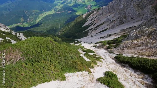 Fast diving drop down flight with a FPV drone through a narrow canyon. Flying very close to the ground in a picturesque valley with a lot of rocks. Aerial cinematic view. Schneeberg, Austria photo