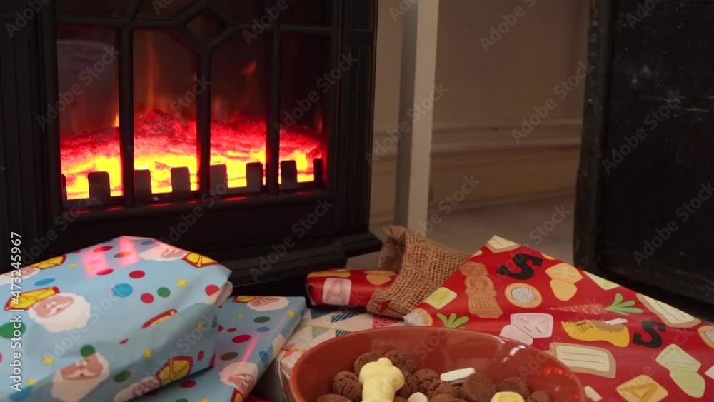 Bowl of Sinterklaas holiday candy and colorful wrapped gifts in front of a fireplace