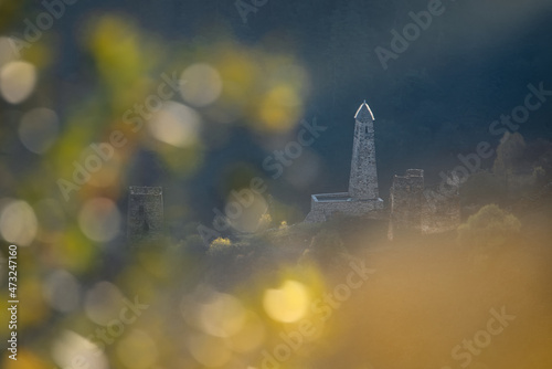 A colorful view of the Erzi tower complex. Beautiful sunny bokeh in the foreground. Clear summer day. Natural background. Ingushetia. Caucasus. photo