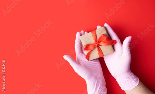 Women's hands in pink medical gloves hold a gift.