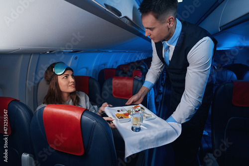 Woman looking at flight steward while taking her meal