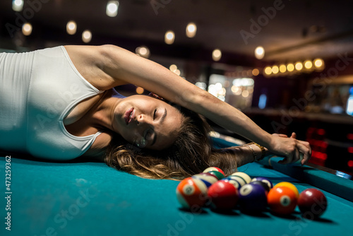 Fototapeta Naklejka Na Ścianę i Meble -  Beautiful lady lying on green snooker table among the balls