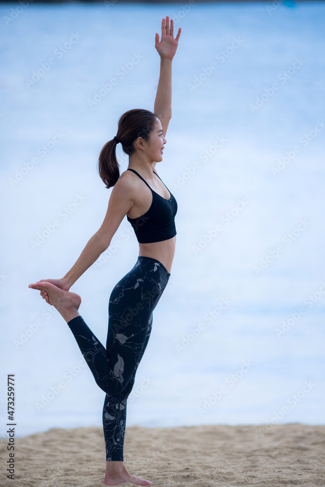 Obraz premium 海のビーチでヨガを練習している若い女性ヨガインストラクター