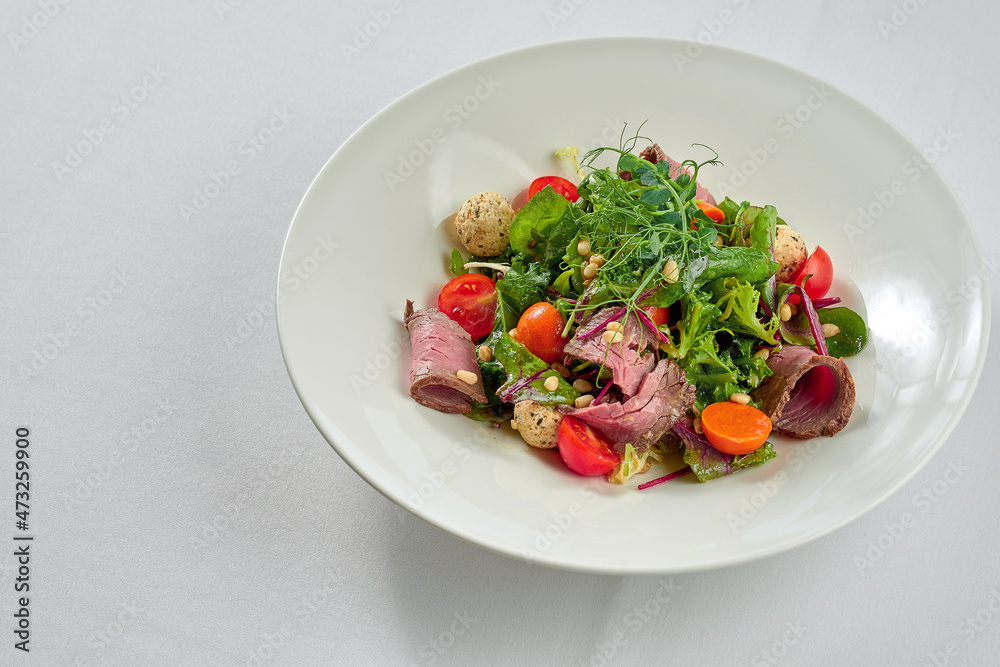 Salad with roast beef and pine nuts in a white plate. Salad with roast beef and pine nuts in a white plate.