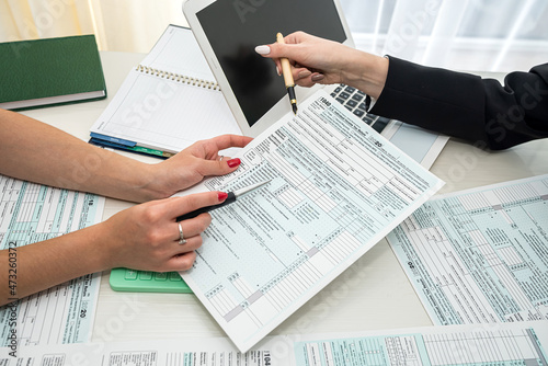 two hand filling us tax form, 1040