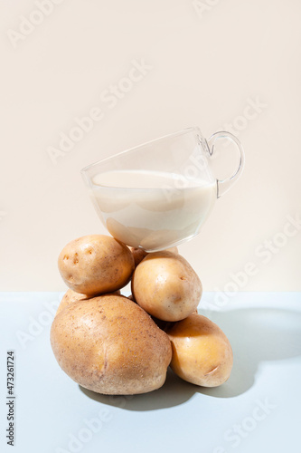 Alternative plant milk. Modern composition with a cup with potato milk that balances on a pile of potatoes