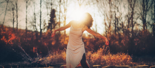 Beautiful woman dancing in nature at sunset.