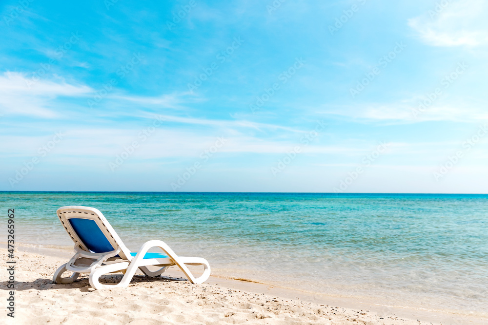 A lone sun lounger stands on the seashore right next to the water A lone sun lounger stands on the seashore right next to the water