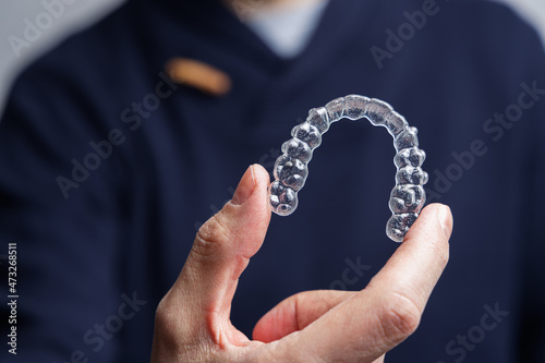 Man holding one transparent aligner. Invisalign orthodontics concept photo