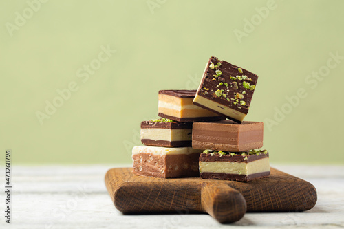 Different cremino - italian chocolate,  originally from Piedmont, composed by different layers, made with gianduja chocolate, coffee, pistacchio and hazelnut paste. Pistacchio color background. photo