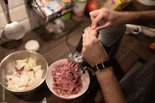 Mincer machine with fresh chopped meat at home kitchen. Preparing ground meat male hands closeup.