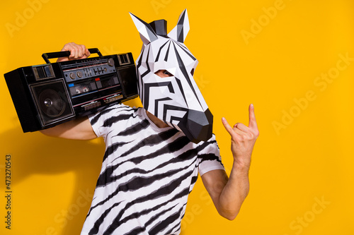 Photo of weird freak guy dj in zebra mask hold boom box song show horned fingers isolated over bright yellow color background