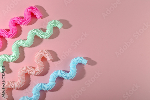 Curved pink blue mint antistress pop tube toy with shadow on pink background. Bright kid toy. Copyspace
