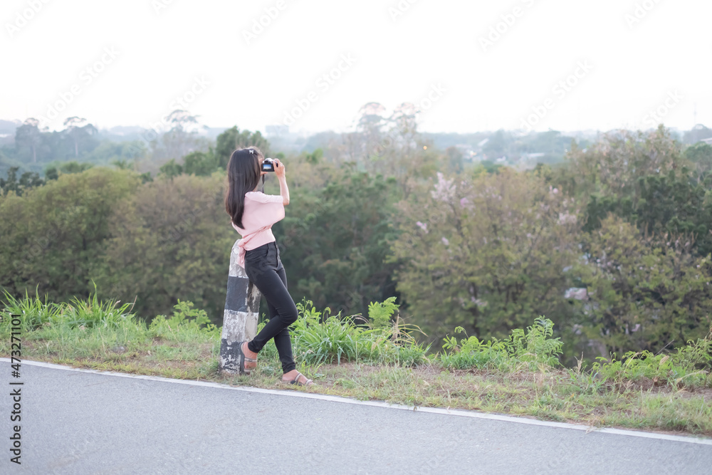 Portrait Alone Woman holding Camera photography take a photo. she standing on side of Road. Tourist vacation Nature Tropical Travel Summer in Holidays concept. Portrait Alone Woman holding Camera photography take a photo. she standing on side of Road. Tourist vacation Nature Tropical Travel Summer in Holidays concept.