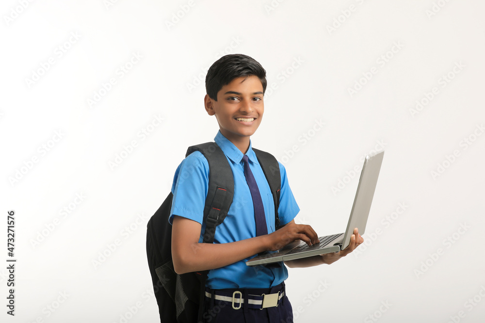 Indian school boy in uniform and using laptop on white background. Indian school boy in uniform and using laptop on white background.