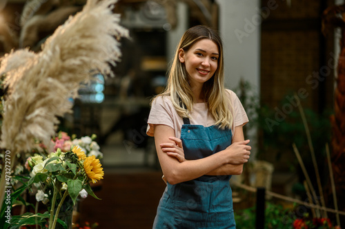 Florist working in flower shop while smiling and looking at a camera