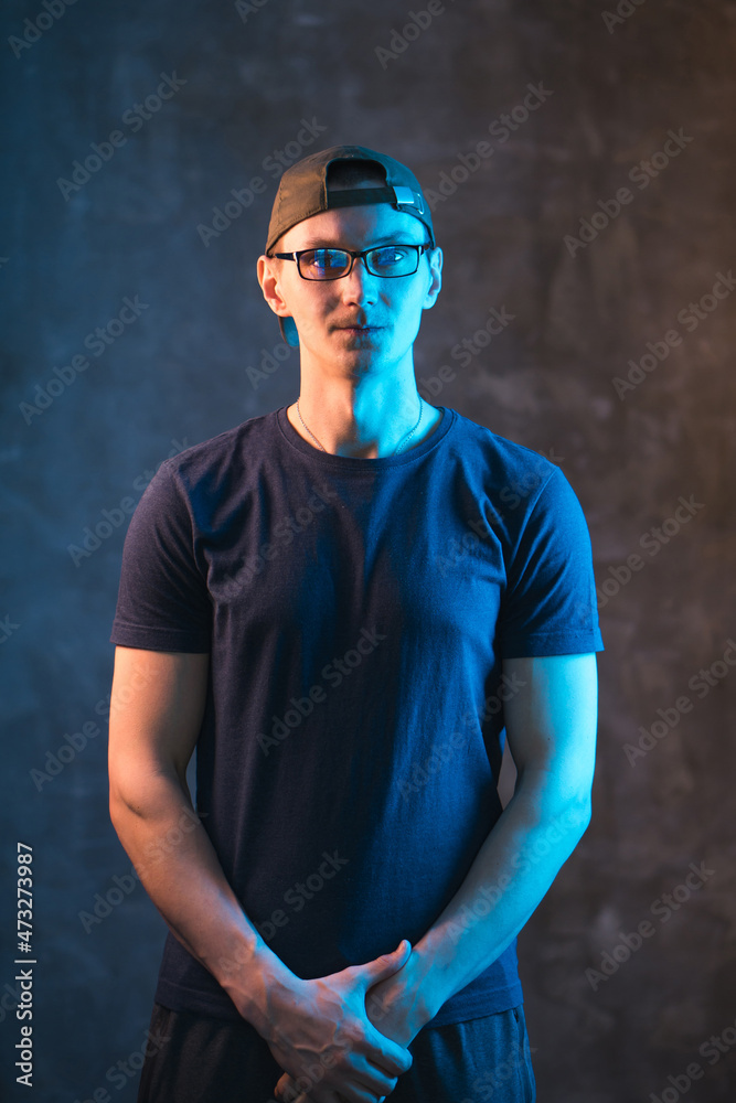 Ordinary guy in cap and glasses lit by neon light. Ordinary guy in cap and glasses lit by neon light.