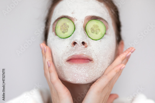 Spa girl applying facial mask with cucumbers. Beauty treatments.