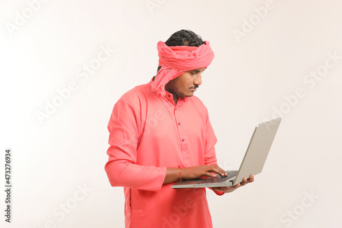 Indian farmer using laptop on white background.