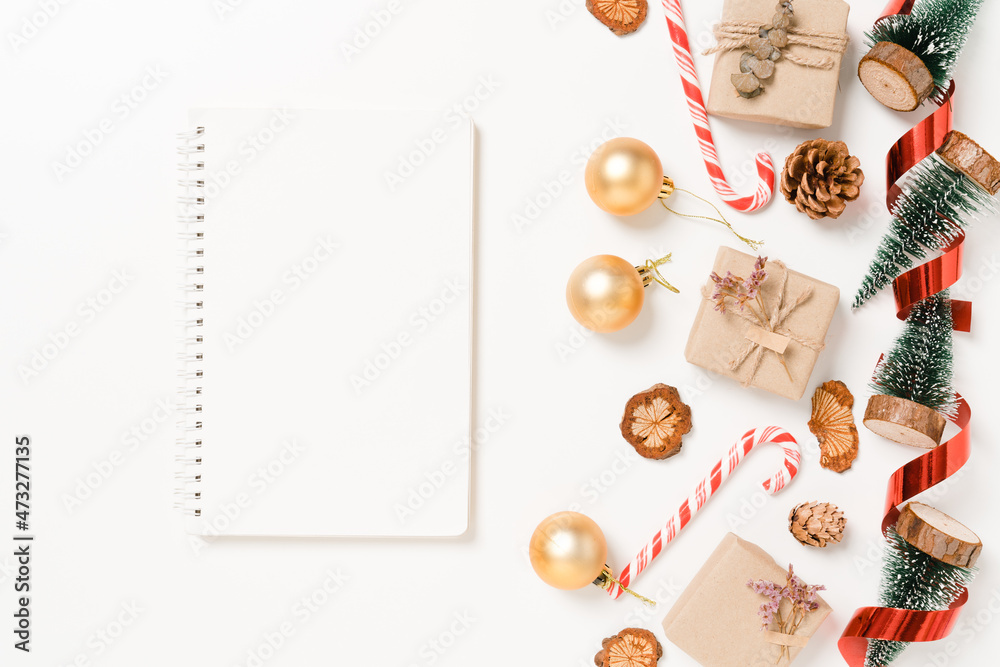 Fototapeta premium Minimal creative flat lay of winter christmas traditional composition and new year holiday season. Top view open mockup black notebook for text on white background. Mock up and copy space photography.