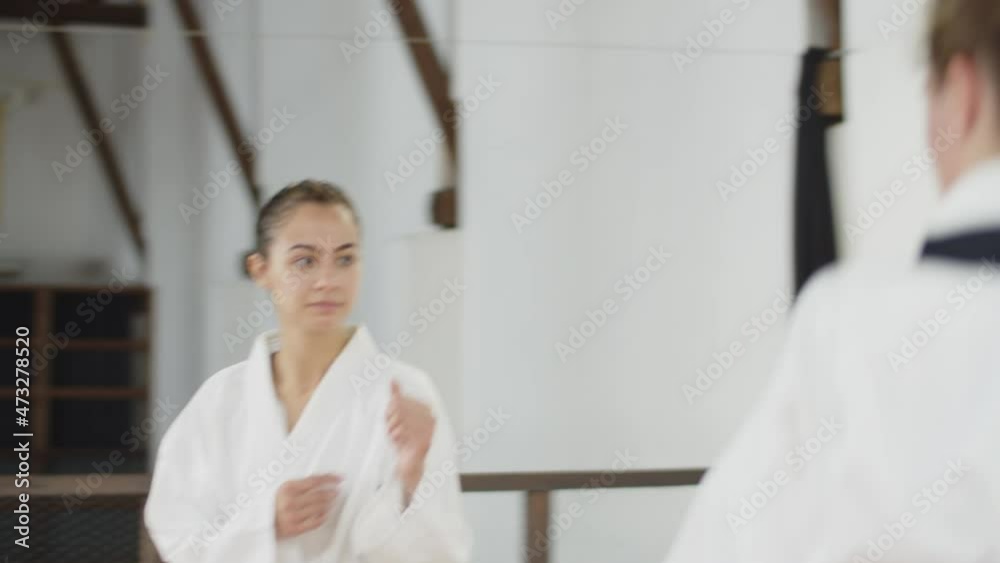 Handheld shot of martial artsists greeting each other in bow. Cheerful girls in kimonos starting karate training in gym, fighting, exercising and improving professional skills. Sport, greeting concept