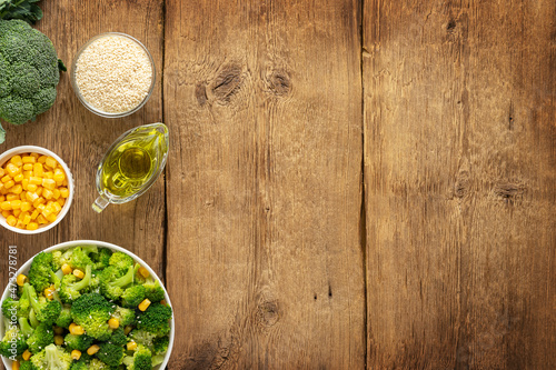 Salad of broccoli and ingredients on wooden background. Top view, copy space.