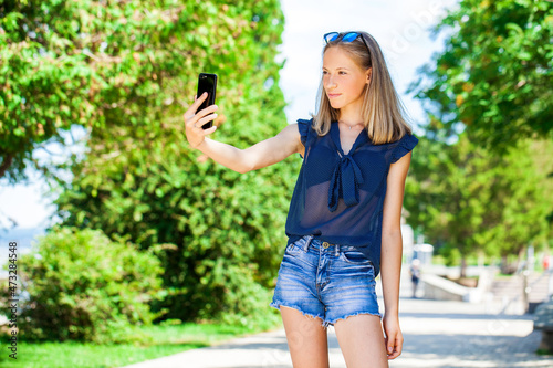 Happy beautiful girl taking pictures of herself on a mobile phone photo