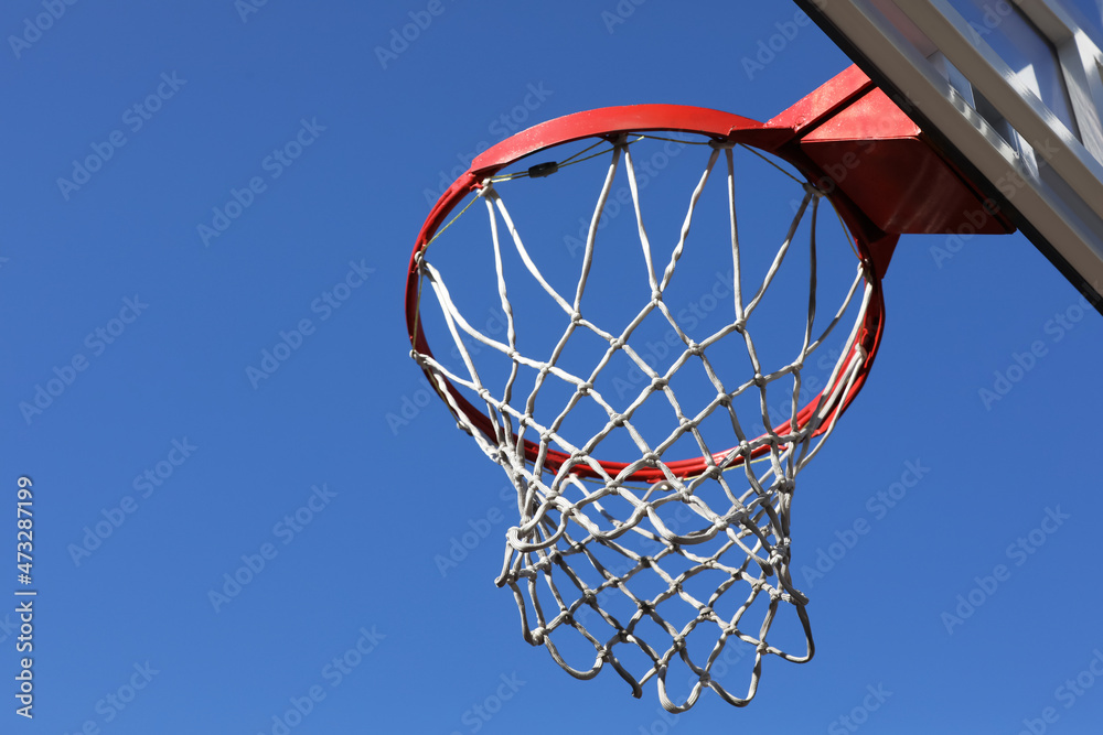 Basketball hoop with net outdoors on sunny day