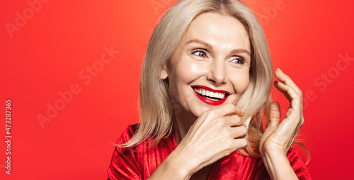 Romantic valentines day and wome beauty concept. Happy mature lady, 60 years old woman in elegant dress and red lipstick, laughing and smiling, touching healthy blond hair