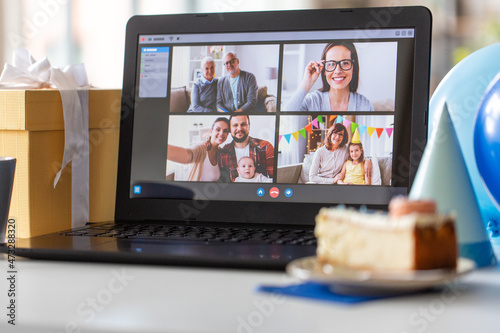 technology and online communication concept - laptop computer with happy people on screen having video call or virtual birthday party at home