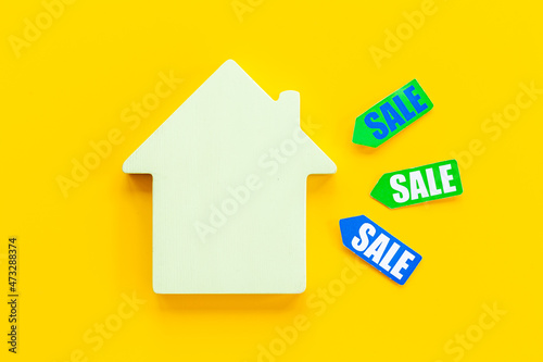 Sale price tag with wooden house figure. House for sale