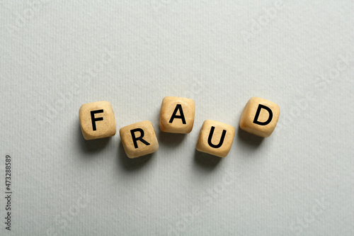 Word Fraud of wooden cubes with letters on light grey background, flat lay