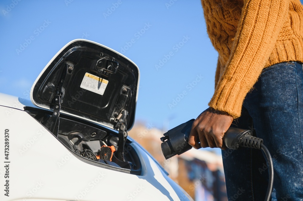 African American man charging his electric car.
