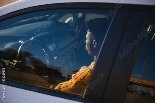 Handsome young African American man in his new high-tech electric vehicle while drinking. Self driving vehicle concept