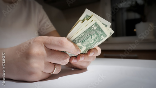 Closeup of stressed upset woman counting her money on kitchen at night. Concept of financial difficulties, poverty, bankruptcy, taxes and rent payment.