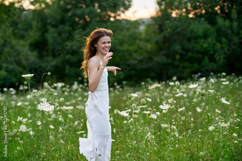 cheerful woman in a field with flowers in a white dress in nature