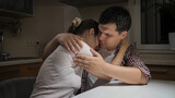 Upset and stressed woman crying and hugging her husband on kitchen at night. Concept of despair, stress, depression, anxiety, family problems, divorce and frustration.