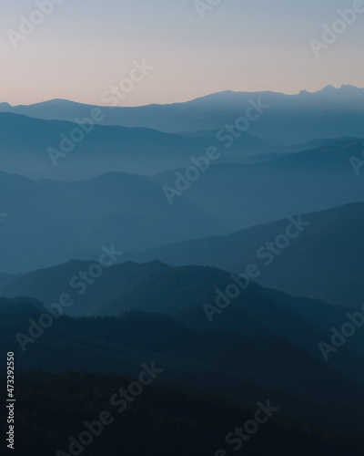 Mountain silhouette layers in the sunset light. Beautiful photography of the nature, blue layered background. Natural gradient. © Derariad