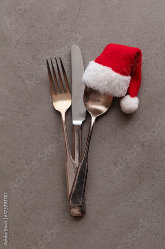 Silver knife fork and spoon with a Santa Claus red festive hat. Christmas meal background