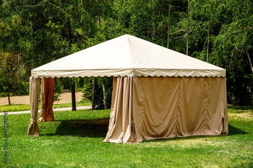 Beige canopy tent on green lawn garden