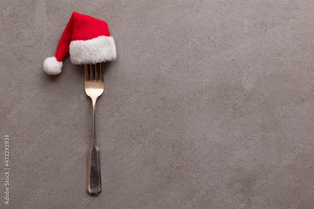 Christmas food background. Fork utensil wearing a festive father Christmas hat