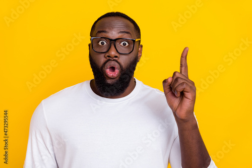 Portrait of impressed guy pointing finger open mouth look camera isolated on yellow color background
