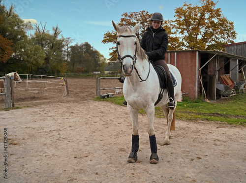 white horse  and rider training on a riding ground photo