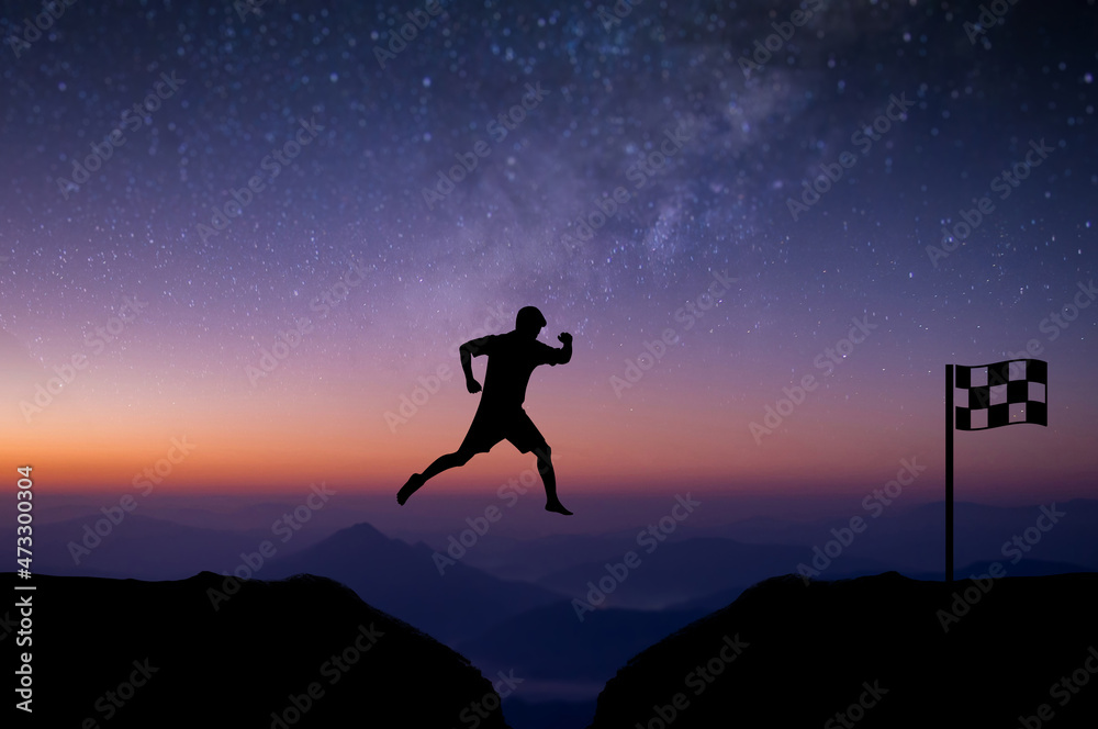 Young man jumping over precipice between two mountains cross the finish line with beautiful night sky, star and Milky Way over the sky. showing determination, freedom, risk, challenge, success. Young man jumping over precipice between two mountains cross the finish line with beautiful night sky, star and Milky Way over the sky. showing determination, freedom, risk, challenge, success.