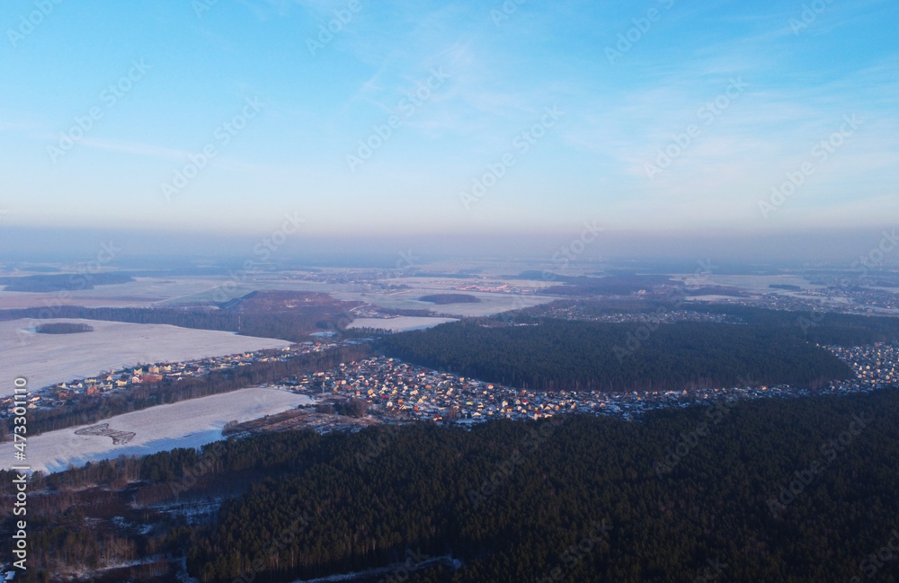 Aerial view of winter snowy landscape with forest and field